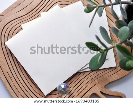 A blank sheet of paper and a white envelope in the middle of the table, top view. concept for the design of a greeting card or invitation card.