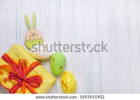 Easter backgrounds for greeting lettering, promotions. Gift box and easter eggs on a light wooden background with figures of wooden rabbits. Easter frame design for text.
