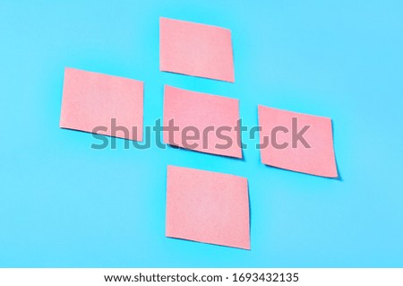 Five pink square blank paper stickers on blue background. Copy space