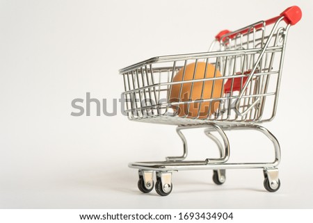 toy little consumer food trolley from steel with red plastic handle on a gray background with one fresh egg inside. empty space right position