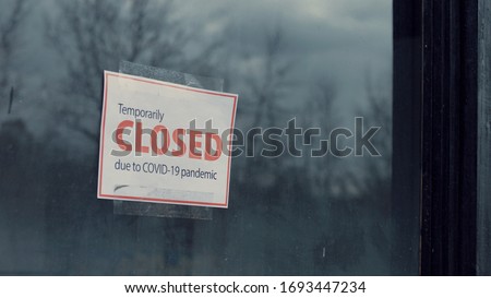 FIXED view of a Temporary closed due COVID-19 pandemic sign hanging on a window. Coronavirus pandemic, small business shutdown Royalty-Free Stock Photo #1693447234