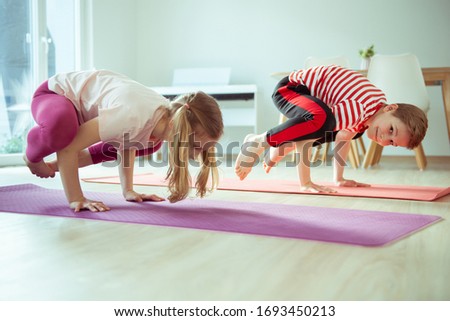 Happy siblings children making yoga at home dueing coronavirus quarantine
