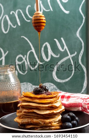Delicious and fluffy American pancakes with blueberries and honey. There's a sign that says "pancakes today" on it. Breakfast and snack concept.