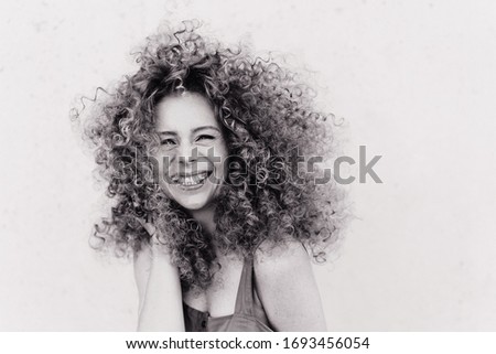 Cute curly blonde with afro hairstyle laughs. plain gray background. emotional photo black and white photo 