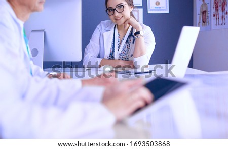 Serious medical team using a laptop in a bright office