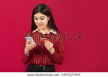 beautiful young woman with credit card and phone on a red background