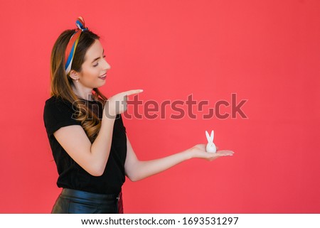 woman's hand holding Easter bunny on red background. Traditional spring holiday food, copy space