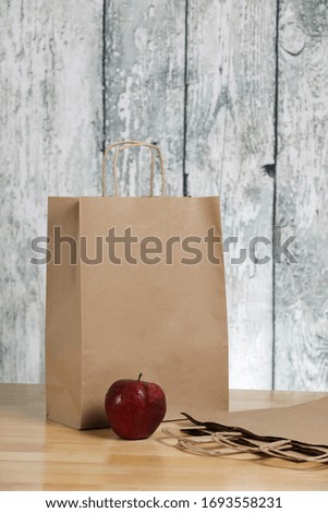 Recycled paper shopping bag , red apple on a wooden background. Eco product. 