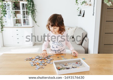 Toddler girl wearing pajamas playing puzzles at home. Stay at home activity for kids.