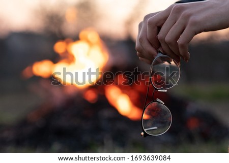 Female hands holding glasses, blurred fire on the background, outdoor photo