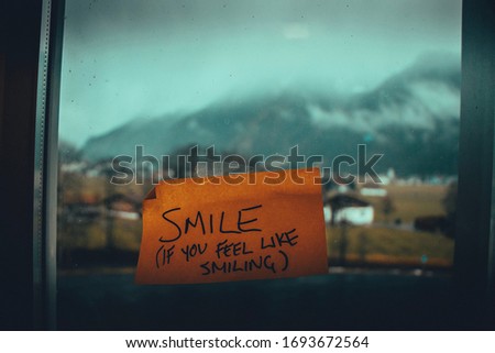  "Smile (if you feel like smiling) sign on the window. Sticky note Motivational quote. Monday inspiration.