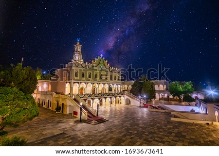 Iconic night view of the illuminated Church Panagia Megalochari (Virgin Mary) against the galaxy in Tinos, Cyclades. It is the patron saint of Tinos island considered as the saint protector of Greece.