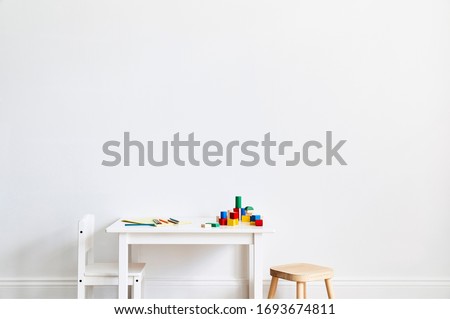 Interior photography of a children's playroom with a little white table and chairs and colourful wooden blocks, space for copy