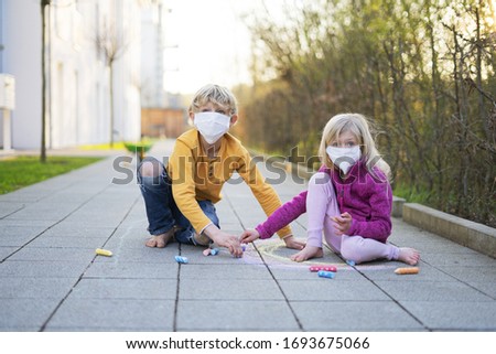 Children with mask playing outside drawing with chulk
