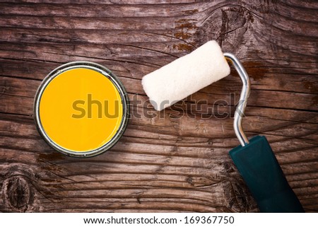 Top View of Small paint roller and color tin can on old wood background. Redecoration and renovation concept.