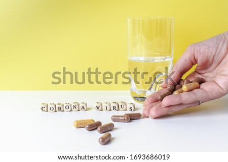 
The inscription corona virus on wooden blocks. Man is drinking pills. fight against corona virus 2019-ncov