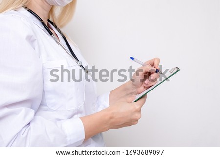 Unrecognizable female woman doctor writing a diagnosis, case medical history on a prescription board. Royalty-Free Stock Photo #1693689097