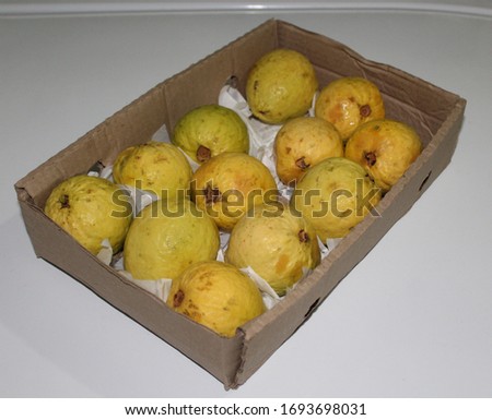 Cardboard box with red guavas on white background
