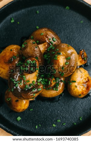 Baked mushrooms in a sauce on a cast-iron plate.