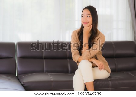 Portrait beautiful young asian woman happy smile relax on sofa in living room interior