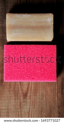 Sponge for dishes and laundry soap flat lay on a wooden background