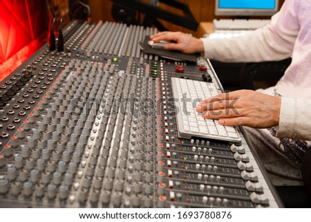 professional male producer, sound engineer hands working on computer and audio mixing console in recording, editing, broadcasting studio. post production concept