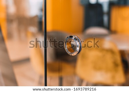 round metal doorknob in the glass door of a modern office