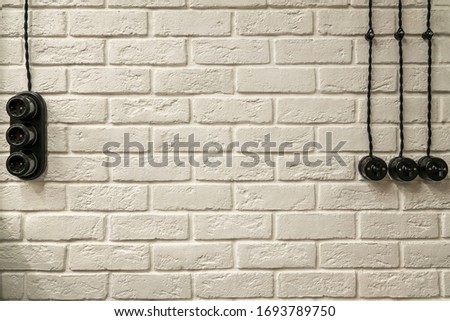 White brick textured wall, with sockets, switches and electrical wiring. loft background