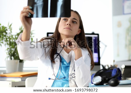 Portrait of serious medical worker examine x ray scan of broken wrist. Modern cabinet with all needed equipment. Professional doctor at work. Healthcare and checkup concept