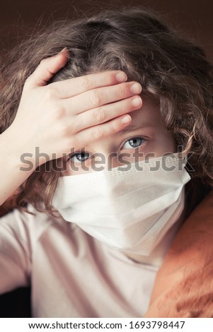 sick child in a mask in bed at home coronavirus