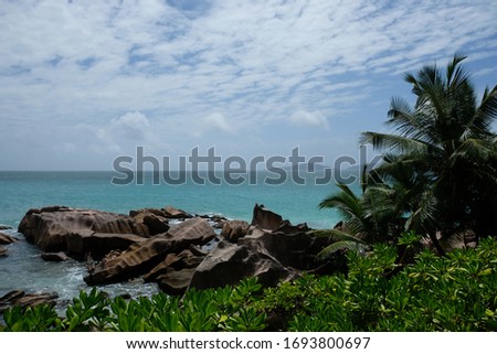 Limestone boulders towering over white sand beaches fringed by lush green foliage, the Seychelles