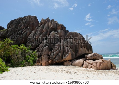 Limestone boulders towering over white sand beaches fringed by lush green foliage, the Seychelles