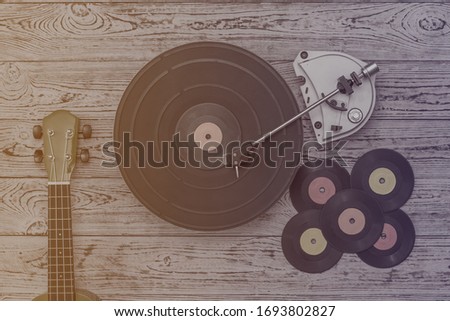 Tinted image of a vintage record player and guitar on a wooden background. Retro technique for playing music.