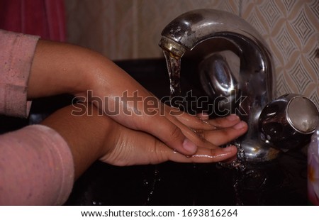 An Indian child washing her hand in wash basin for prevention of germs and Corona Virus , Omicron, delta virus