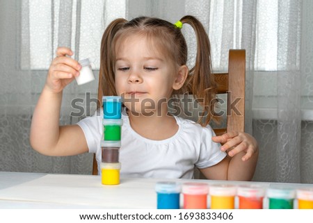 quarantined girl sits and builds a tower of cans of colored paints, stay home