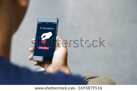 e-donation concept.close-up of man hands make an online donate via mobile phone Royalty-Free Stock Photo #1693879516