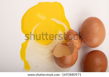 A broken chicken egg and eggs scattered on a white background. Close up.
