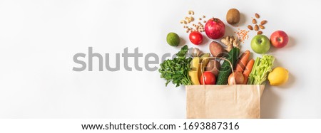 Delivery healthy food background. Vegan vegetarian food in paper bag vegetables and fruits, nuts and grains on white, copy space, banner.Grocery shopping food supermarket and clean eating concept. Royalty-Free Stock Photo #1693887316