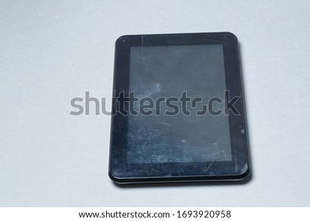 Black scratched tablet with a protective film on a gray background. Protect your device screen