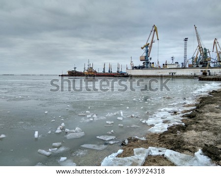 snow on the seashore against the background of the seaport