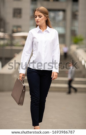 Young beautiful blonde business lady in classic look walking on the street with Briefcase Designer Leather Laptop Satchel Portfolio Messenger Bag.  different color of bag and no logo.