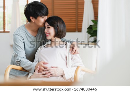 Asian man are kiss his wife forehead, she is pregnant and will have a baby. Couple life, Motherhood, family and kids relationship, new born baby, healthy pregnancy concept.
 Royalty-Free Stock Photo #1694030446