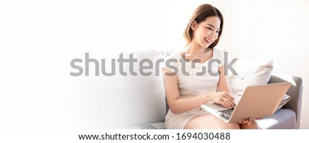 Beautiful young asian woman in white t-shirt working from home with laptop  in sunshine background by video call meeting online app. Remote communication, self quarantine prevent coronavirus concept.
 Royalty-Free Stock Photo #1694030488