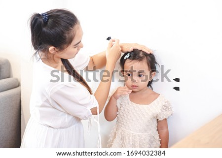 Asian mother use tape for measure her daughter's height. Mom and kids, education, family relationship, child care, children growth evolution concept.
 Royalty-Free Stock Photo #1694032384