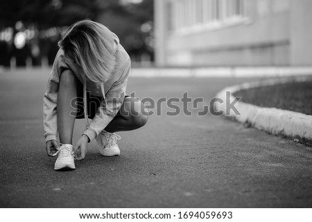 young athlete. beautiful girl athlete tying shoelaces on sneakers. beautiful girl athlete sitting tying shoelaces on white sneakers. Healthy lifestyle concept. black and white photo