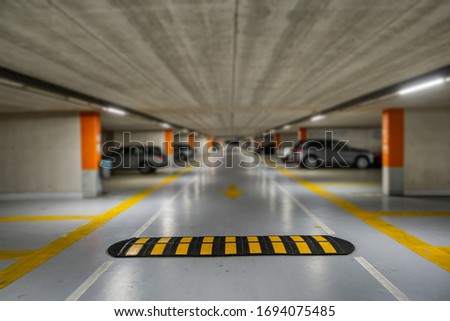 Yellow markings with blurred modern cars parked inside closed underground parking lot. Royalty-Free Stock Photo #1694075485