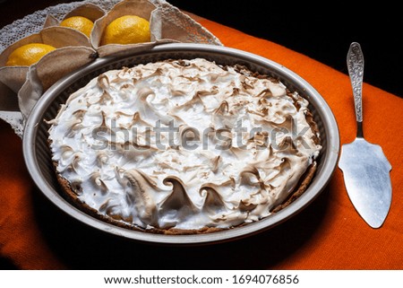 
Meringue lemon cake with a cup of coffee on a white wooden background