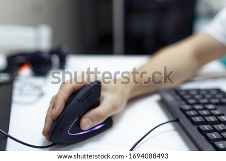 In the man’s hand, a vertical ergonomic computer mouse-joystick is used. Royalty-Free Stock Photo #1694088493