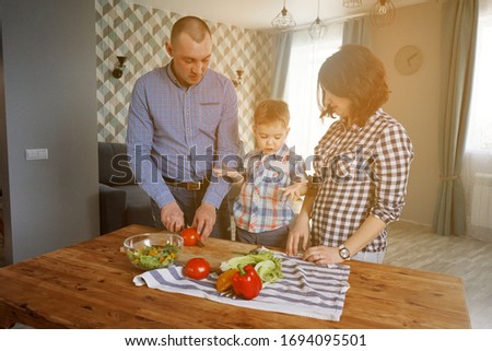 Husband and wife and their little son are preparing dinner together. Man and woman in the kitchen with their child cooking. What to do during quarantin. Stay home Self-isolation.