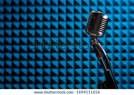 Silhouette of retro microphone on blue acoustic foam panel background